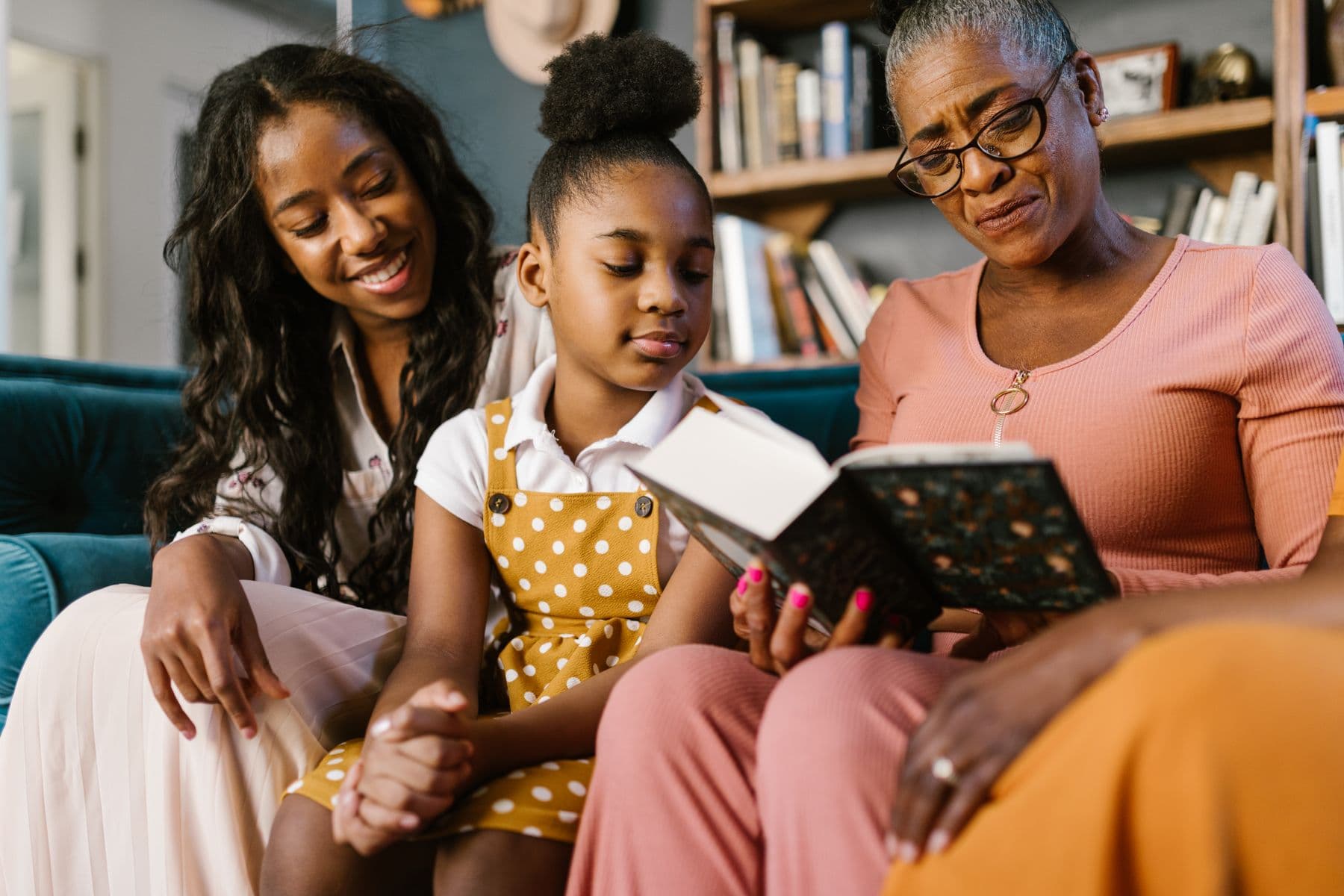 Three generations of a family reading together at home.